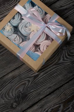 Lokum mavisi ve pembe. El işi ambalajında yatıyor. Mistik kar taneleriyle süslenmiş. Kutu bir kurdeleyle fiyonka bağlanmış. Siyah çam tahtalarında.