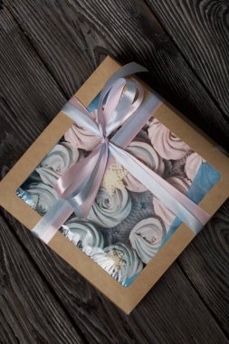 Lokum mavisi ve pembe. El işi ambalajında yatıyor. Mistik kar taneleriyle süslenmiş. Kutu bir kurdeleyle fiyonka bağlanmış. Siyah çam tahtalarında.