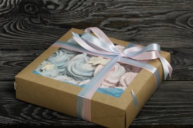 Lokum mavisi ve pembe. El işi ambalajında yatıyor. Mistik kar taneleriyle süslenmiş. Kutu bir kurdeleyle fiyonka bağlanmış. Siyah çam tahtalarında.