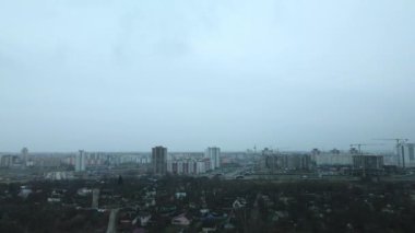 Şehir parkının içindeki nehir. Sonbaharın sonu, bulutlu. Yapraksız ağaçlar ve nehir kıyısında kurumuş sazlıklar. Şehir ufukta görünüyor. Hava fotoğrafçılığı.