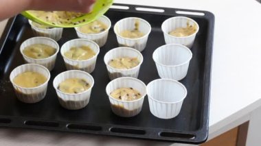 Bir kadın hamuru kek tepsisine koyar. Çikolatalı ve kuru üzümlü kek hazırlıyor. Yukarıdan yakın çekim..