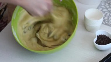 Bir kadın çikolatalı ve kuru üzümlü kek hazırlıyor. Hamuru konteynırda karıştırıyor. Çikolataya yakın. Yakın çekim.