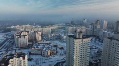 Şehir üzerinde uçuş. Modern çok katlı binalar. Kış şehri manzarası. Sisli bir sis görünür. Hava fotoğrafçılığı.