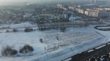 Şehir üzerinde uçuş. Kış şehri manzarası. Yakınlarda bir demiryolu hattı var. Sisli bir sis görünür. Hava fotoğrafçılığı.