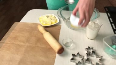 Bir kadın konteynırda bisküvi yapmak için gereken malzemeleri karıştırıyor. Marshmallow sandviçi pişiriyorum. Malzemeler ve aletler masaya serildi..