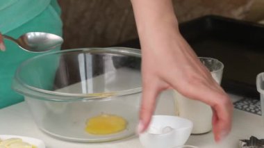 Bir kadın konteynırda bisküvi yapmak için gereken malzemeleri karıştırıyor. Marshmallow sandviçi pişiriyorum. Malzemeler ve aletler masaya serildi. Yakın çekim..