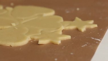 Kadın rulo hamurla çalışıyor. Hamuru kalp ve kar taneleri şeklinde parçalara ayırır. Marshmallow sandviçi hazırlıyor. Yakın çekim..