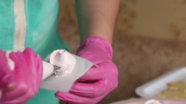 Bir kadın pasta torbasıyla marşmelov çiçeği yapıyor. Yakından çekilmiş..