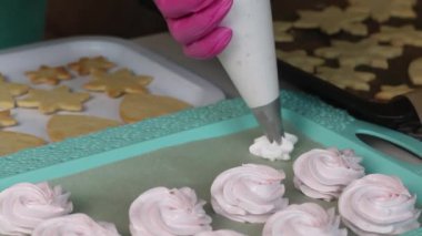 Bir kadın marşmelov yapar. Yakınlardaki bir tepside bisküviler var. Yakından çekilmiş..