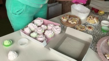 Bir kadın lokumları bir kutuya koyuyor. Değişik şekil ve boyutlarda şekerlemeler. Şekerlemeler masanın üzerine yayılmış.
