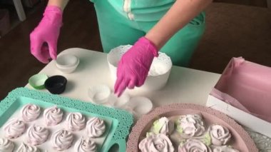 Bir kadın ambalaj için marşmelov hazırlar. Şekerlemeler masanın üzerine yayılmış..