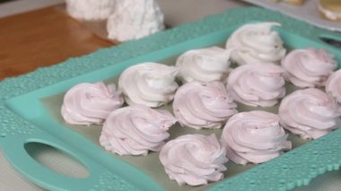 Kadın marşmelov yapıyor. Tatlılar masanın yüzeyine yayılmış. Yakın çekim..