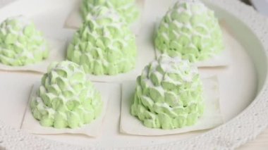 Bir kadın lokum külahlarına şeker serpiyor. Beyaz ve açık yeşil renkli lokum konileri. Yakın çekim.