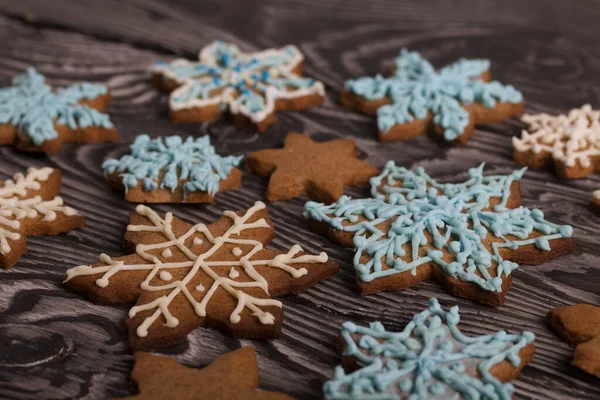 Kar tanesi şeklinde zencefilli kurabiye. Şeker jölesiyle süslenmiş. Kar tanesi şeklinde zencefilli kurabiye. Kara tahtaya uzan. Yakın çekim..