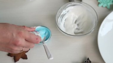Kadın zencefilli ekmeği süslemek için krema yapıyor. Şekeri suyla renklendirir. Yakın plan..