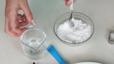 Kadın zencefilli ekmeği süslemek için krema yapıyor. Su ve krema karışımı. Yakınlarda bir boya tüpü var. Yakın plan..