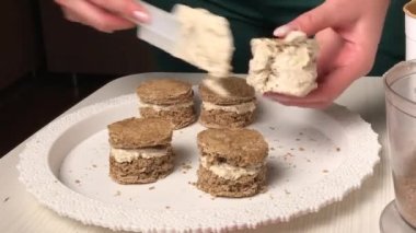 Bir kadın bisküvi keki yapar. İş yerlerine tereyağı kremi sürüyor. Genel plan..