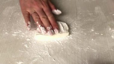 Bir kadın ballı pudra şekeri ve merdaneli jelatin serpiyor. Hamur işi mastiği yapıyor. Yakın plan..