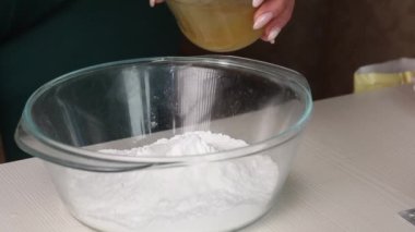 Kadın balla çözünmüş jelatini karıştırıyor. Hamur işi mastiği yapıyor. Yemek pişirmek için malzemeler masaya yayıldı. Yakın plan..