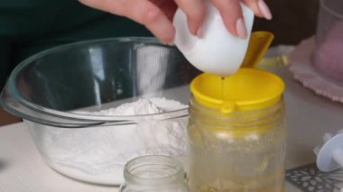 Kadın jelatini eritiyor ve bala ekliyor. Hamur işi mastiği yapıyor. Yemek pişirmek için malzemeler masaya yayıldı. Yakın plan.