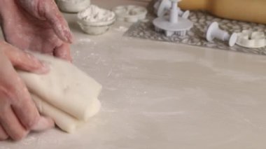 Bir kadın pudra şekerinden şekerleme mastiği yapar. Elleriyle karıştırıyor, pudra şekeri ekliyor. Yakın plan.