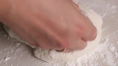 Bir kadın pudra şekerinden şekerleme mastiği yapar. Elleriyle diz çöküp pudra şekeri ekliyor. Yakın plan..
