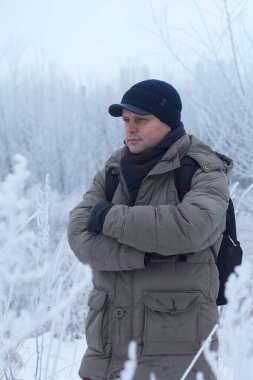 Kışın giyinmiş bir adam. Etrafta karla kaplı bir manzara var. Erkek portresi. Yakın plan.