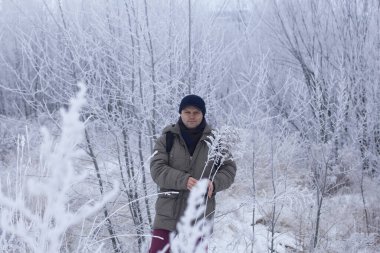 Kışın giyinmiş bir adam. Etrafta karla kaplı bir manzara var. Erkek portresi. Yakın plan.