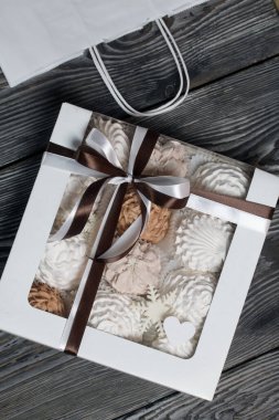 Hediye kutusunda ev yapımı marşmelov. Fiyonka bağlanmış bir kurdeleyle bağlanmış. Siyah çam tahtalarında.