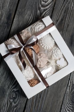 Hediye kutusunda ev yapımı marşmelov. Fiyonka bağlanmış bir kurdeleyle bağlanmış. Siyah çam tahtalarında.