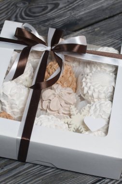 Hediye kutusunda ev yapımı marşmelov. Fiyonka bağlanmış bir kurdeleyle bağlanmış. Siyah çam tahtalarında.