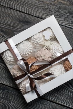 Hediye kutusunda ev yapımı marşmelov. Fiyonka bağlanmış bir kurdeleyle bağlanmış. Siyah çam tahtalarında.