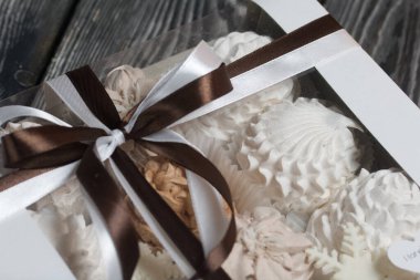 Hediye kutusunda ev yapımı marşmelov. Fiyonka bağlanmış bir kurdeleyle bağlanmış. Siyah çam tahtalarında.