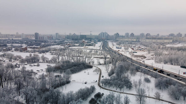 Winter city garden. Trees in the snow. Flying over a snow-covered park. Aerial photography.