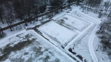 Karla kaplı bir şehir parkında bir spor sahasının üzerinde uçmak. Hava fotoğrafçılığı.