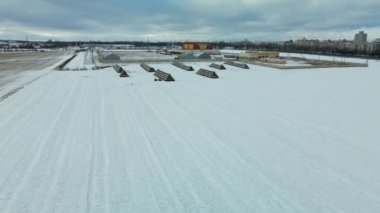 Flying over a snowy field. Straw bales are stacked. Traces of agricultural tillage are visible under the snow. Aerial photography.
