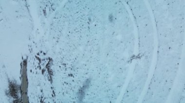 Flying over a snowy field. Traces of agricultural tillage are visible under the snow. Aerial photography.