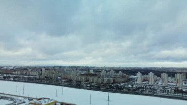Flying over a snowy field. The city is visible on the horizon. Aerial photography.