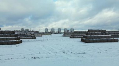 Flying over a snowy field. Straw bales are stacked. Traces of agricultural tillage are visible under the snow. Aerial photography.