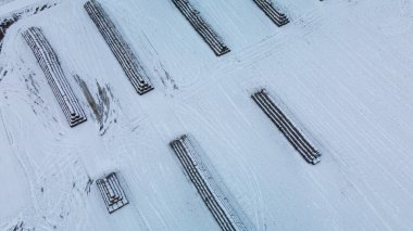 Flying over a snowy field. Straw bales are stacked. Traces of agricultural tillage are visible under the snow. Aerial photography.