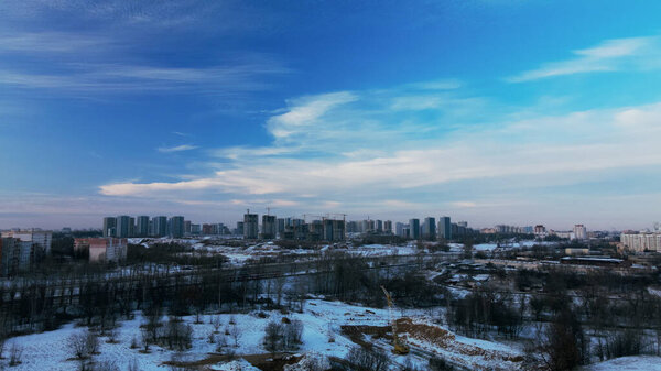 Flying over a snowy park. The city is visible on the horizon. Aerial photography.