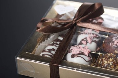 Candies in chocolate glaze. In a gift box. Tied with a ribbon tied into a bow. On a black background.