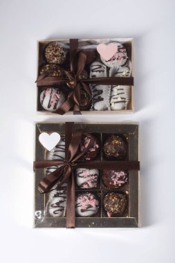 Candies in chocolate glaze. In a gift box. Tied with a ribbon tied into a bow. On white background.