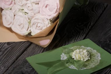 A bouquet in craft paper and a greeting card. Marshmallow bouquet. Roses from marshmallows. Close-up.