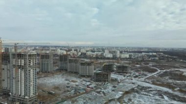 Construction site. Construction of modern high-rise buildings. Work construction cranes. Snow covered earth. Aerial photography.