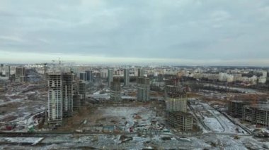 Construction site. Construction of modern high-rise buildings. Work construction cranes. Snow covered earth. Aerial photography.
