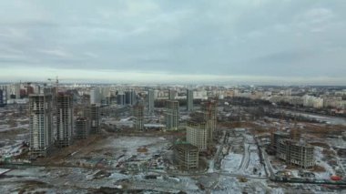 Construction site. Construction of modern high-rise buildings. Work construction cranes. Snow covered earth. Aerial photography.