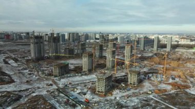 Construction site. Construction of modern high-rise buildings. Work construction cranes. Snow covered earth. Aerial photography.