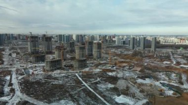 Construction site. Construction of modern high-rise buildings. Work construction cranes. Snow covered earth. Aerial photography.