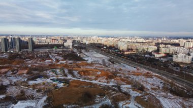 Construction site in a city vacant lot. Close to populated urban areas. Traces of heavy construction equipment are visible on the ground. Snow covered earth. Aerial photography.